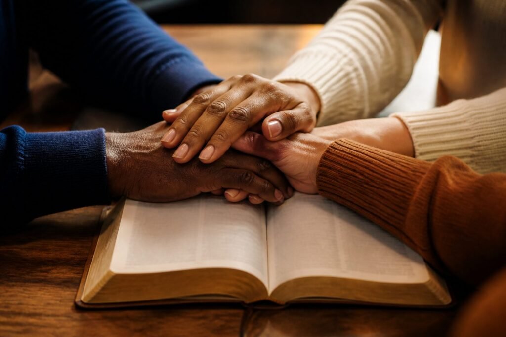 Hands joined in prayer over an open Bible