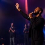 A worship leader singing with hands raised during a Christ Peace Church service